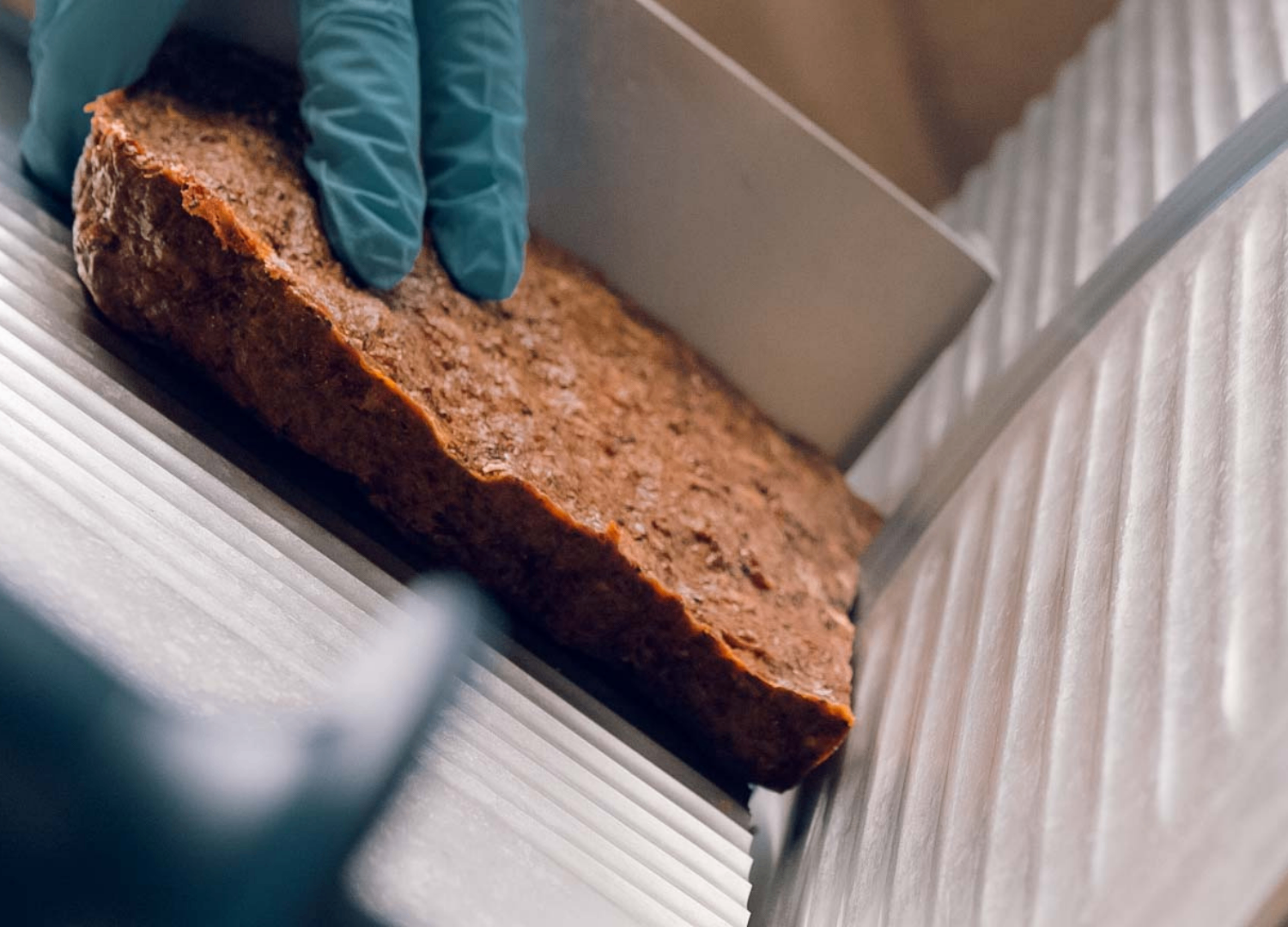 A baked loaf being guided through the slicer