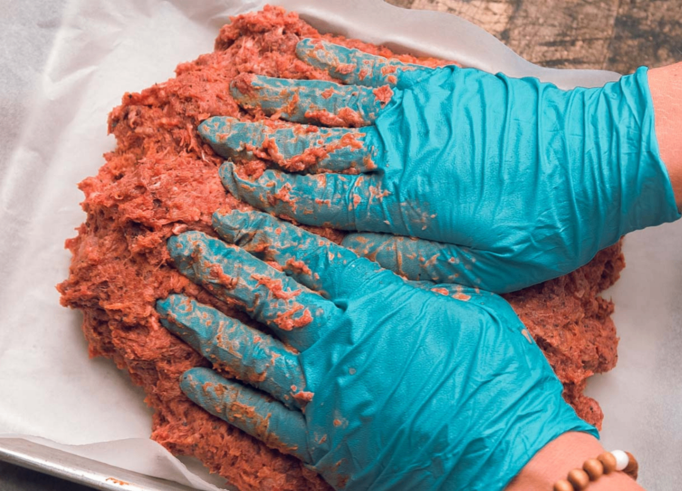Kitchen team hand-pressing a batch into a baking tray